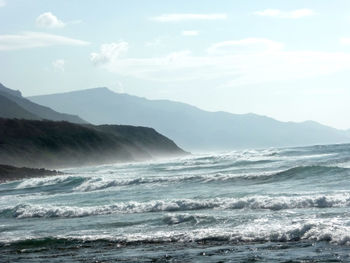 Scenic view of sea and mountains against sky