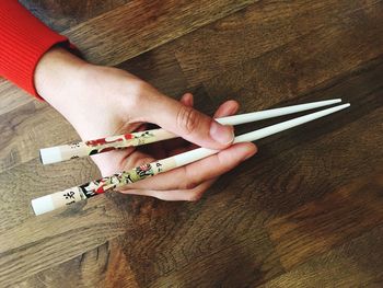 Cropped hands holding chopsticks at table