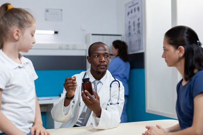 Doctor showing medicine to woman at hospital