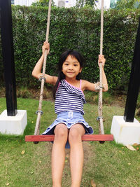 Portrait of girl swinging in park