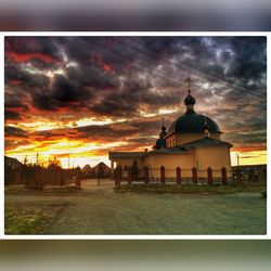 Silhouette of building against cloudy sky at sunset