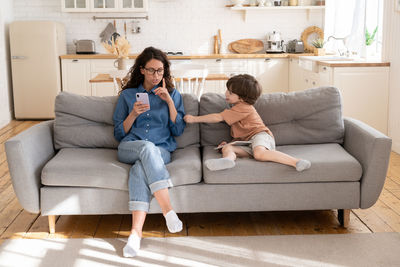 Full length of woman sitting on sofa