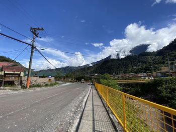 Road by electricity pylon against sky in city