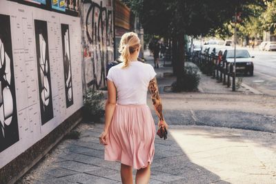 Rear view of woman standing on footpath in city