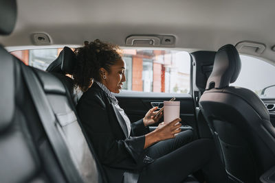 Side view of businesswoman using smart phone while sitting in car