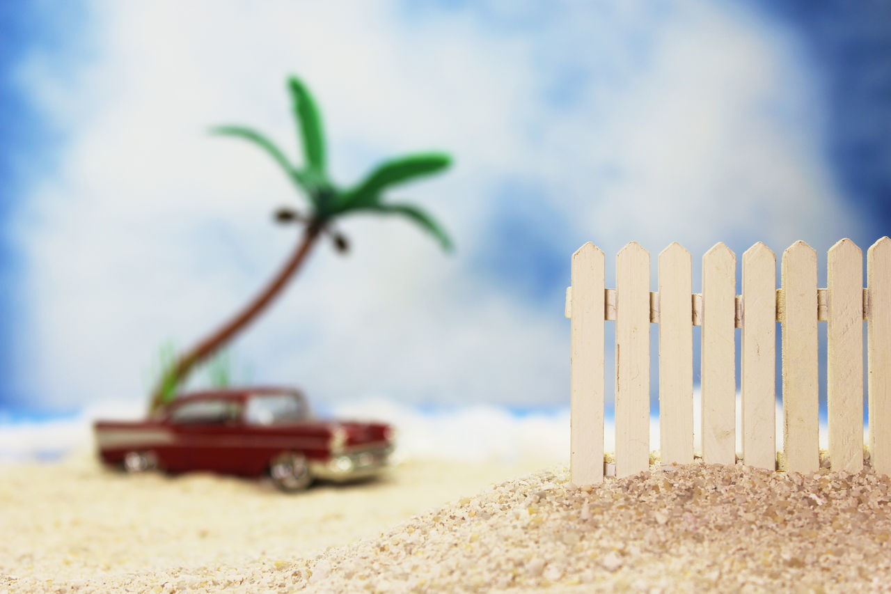 CLOSE-UP OF TOY ON SAND AGAINST SKY