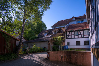 Road amidst trees and buildings against sky