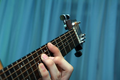 Cropped hand of man playing guitar indoors