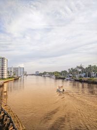 Scenic view of river by buildings against sky