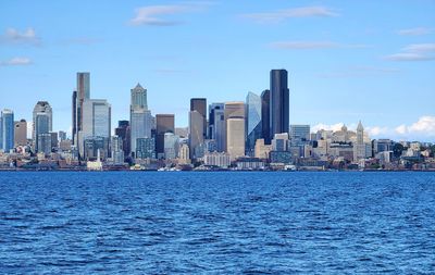 Sea by buildings in city against sky