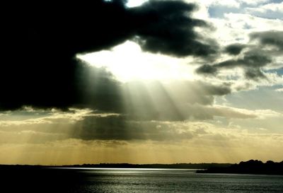 Sun shining through clouds over sea