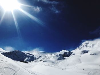 Low angle view of snowcapped mountains against blue sky