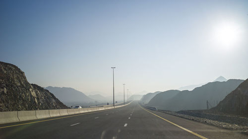 Road by mountains against clear sky