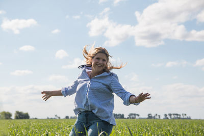 Woman with umbrella on field against sky