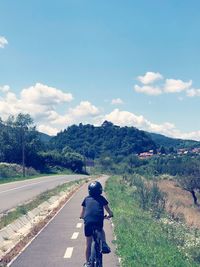 Rear view of man riding motorcycle on road against sky