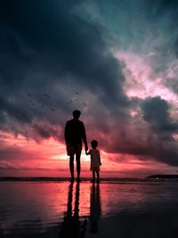 Father and son watching the sunset at a beach - the burning clouds 