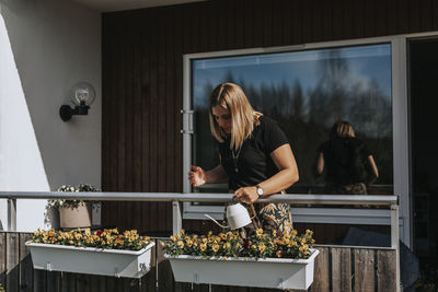 Woman watering flowers on balcony