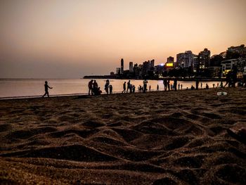 People on beach against sky during sunset