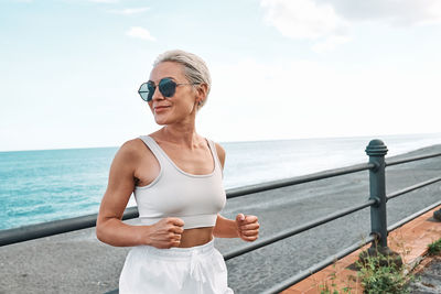 Young beautiful sportive woman training over seaside promenade. workout outdoors by the sea.