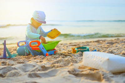 Rear view of boy playing with sand at beach