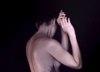 Side view of young woman against black background