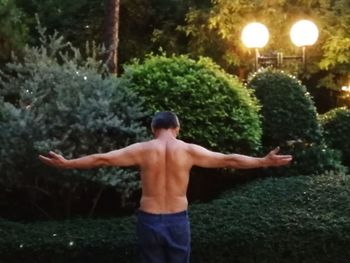 Rear view of shirtless man standing in yard