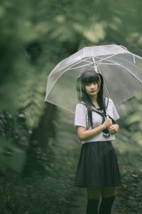 Young student with umbrella standing in park