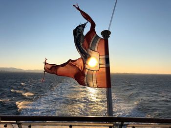 Man in sea against clear sky during sunset