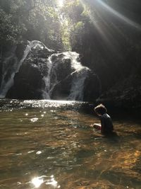 Man sitting on rock by river