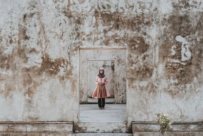 Full length of woman standing against wall