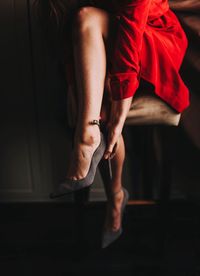 Low section of woman putting on high heels at home