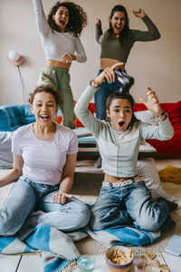 Cheerful female friends having fun playing video game at home