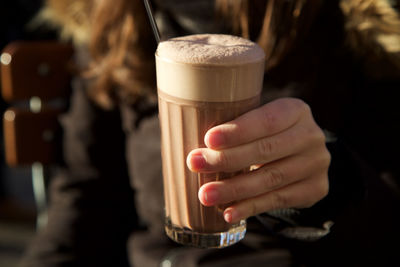 Midsection of woman holding coffee in glass