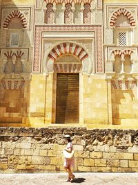 Full length of woman standing against brick wall