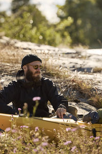 Man sitting near kayak on rocky coast