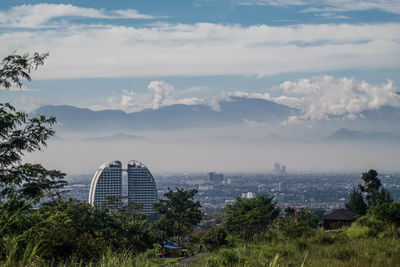 View of buildings in city against cloudy sky