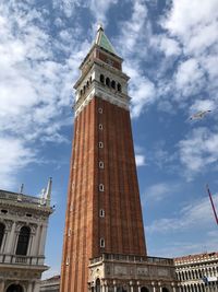 Low angle view of campanile and buildings against cloudy sky