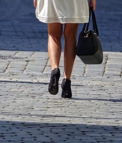 Low section of woman standing on zebra crossing