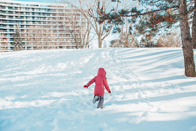 Girl child in warm clothes running in snow park outside. child kid having fun on winter day