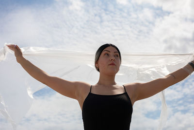 Woman with arms raised standing against sky