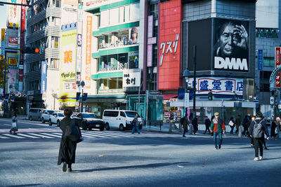 People walking on road against buildings in city