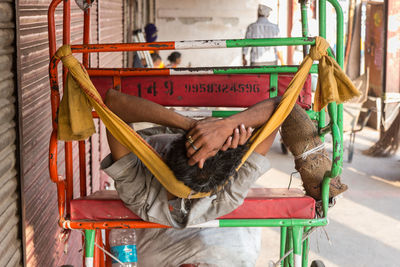 Man sleeping on jinrikisha on footpath