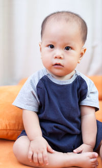 Close-up of toddler sitting on sofa at home