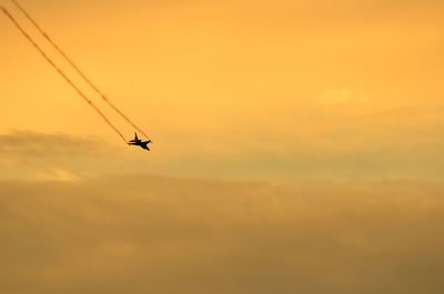 Low angle view of silhouette airplane against sky during sunset