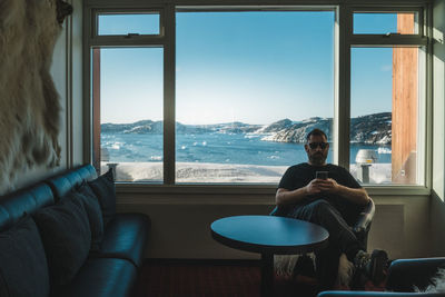 Rear view of man sitting on chair at home