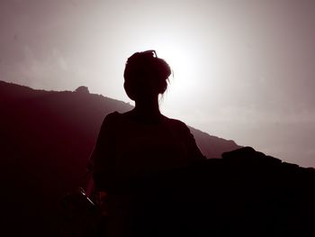 Low angle view of silhouette woman standing on mountain against sky