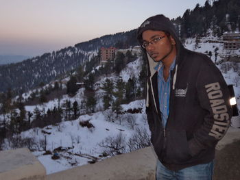 Man standing in sunglasses against sky during winter