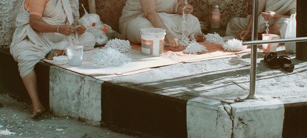 Low section of woman making garlands