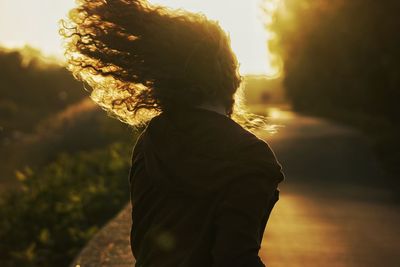 Rear view of woman standing at sunset