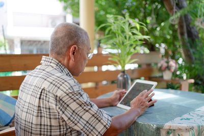 Man using digital tablet while sitting by table